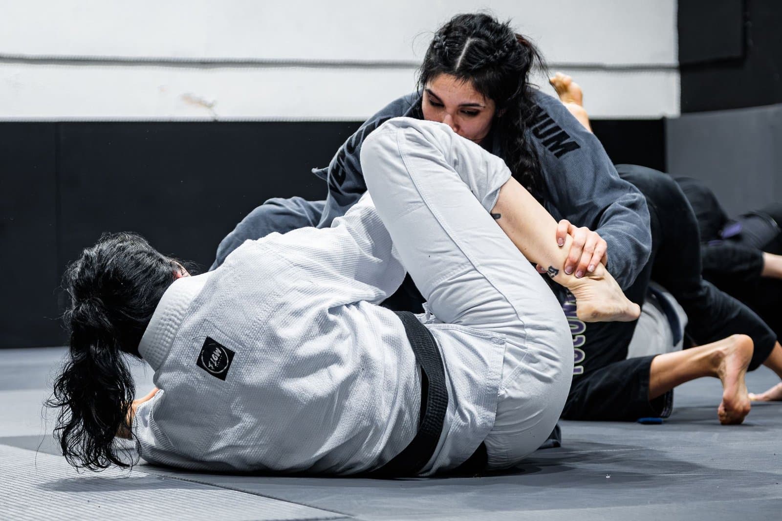 Atleta pressionando por cima na passagem de guarda no jiu-jitsu durante treino de kimono. Foto de Eduard Perez via Pexels