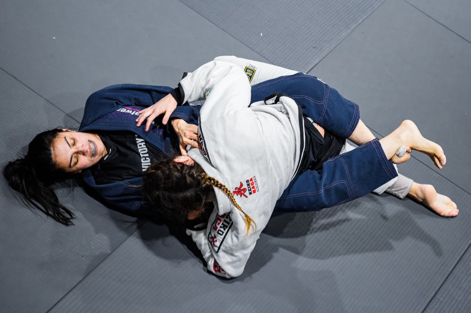 Dupla treinando Jiu-Jitsu no tatame, o tipo de rolamento que a planilha de treino de jiu jitsu ajuda a registrar depois da aula