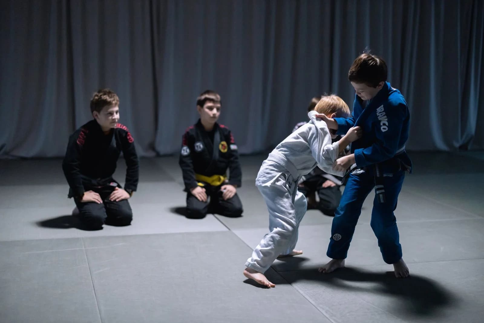 Crianças treinando Jiu-Jitsu de kimono, uma delas com faixa amarela do sistema infantil. Foto de cottonbro studio via Pexels.